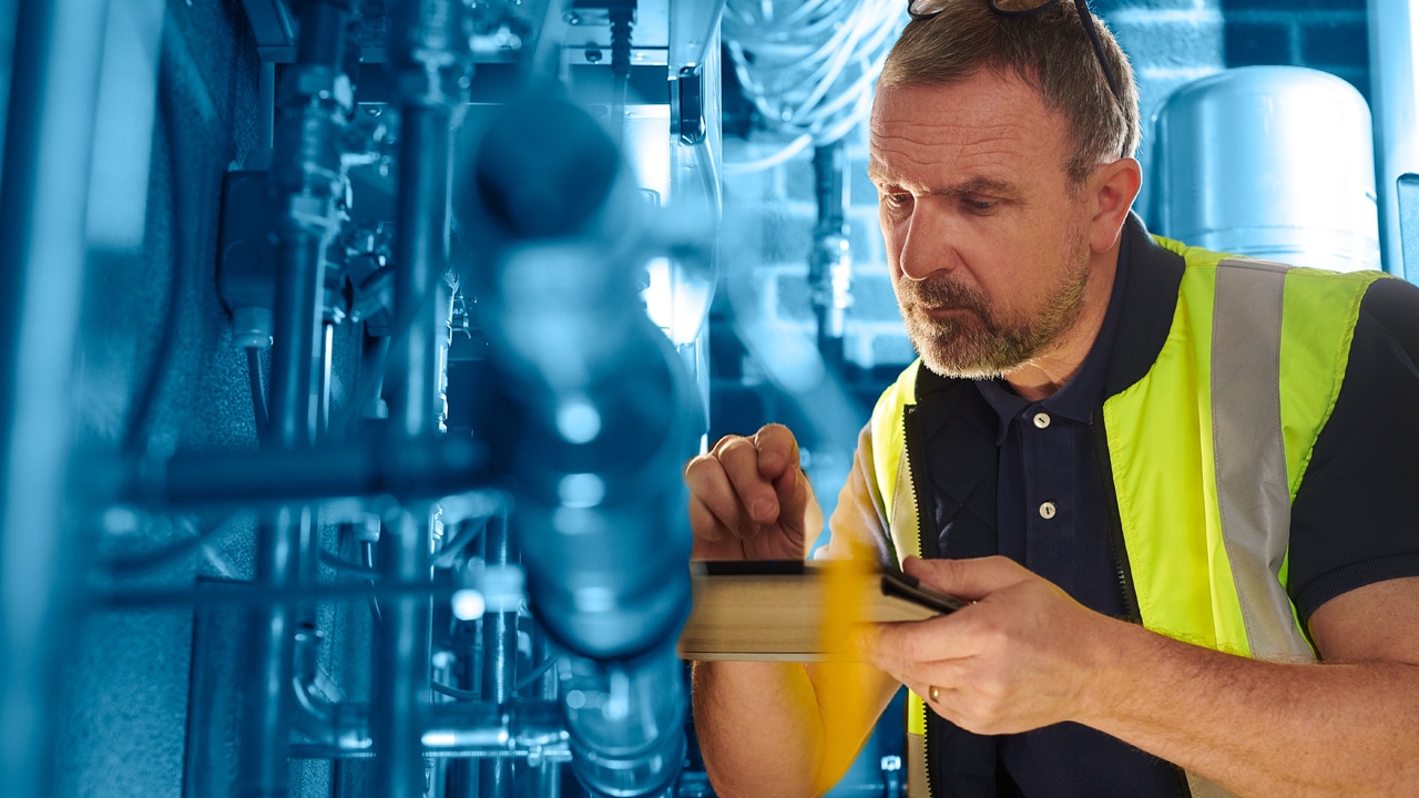 Man In Utility Vest Holding iPad Inspecting Plumbing
